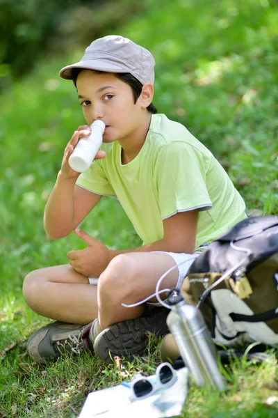 TeNiño sentado en la hierba bebiendo leche bebida — Foto de Stock