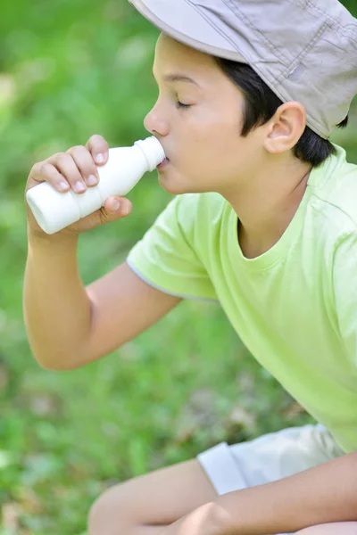 Teyoung ragazzo che si siede nell'erba bere bere il latte — Foto Stock