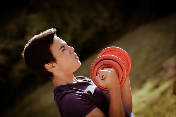 Adolescente levantando um haltere, atlético, esporte — Fotografia de Stock