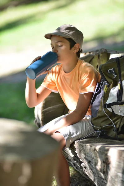 若い男の子に座って水を飲んで — ストック写真