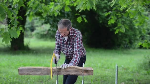 Senior man zagen een log handzaag closeup — Stockvideo