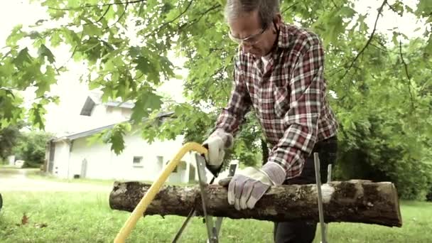 Senior man zagen een log handzaag closeup — Stockvideo