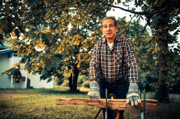 Senior man sawing a log handsaw closeup — Stock Photo, Image