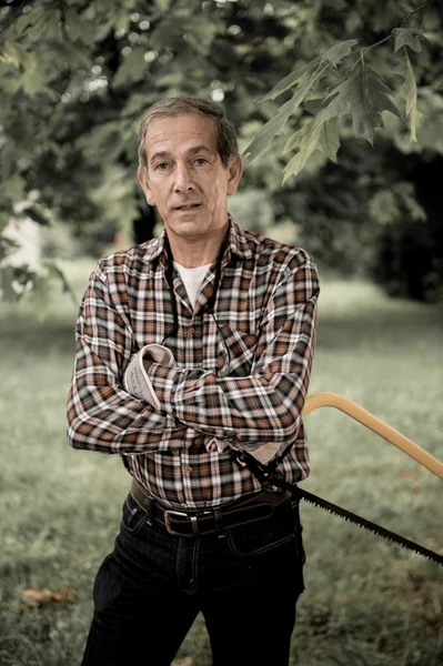 Hombre mayor aserrando una sierra de mano de madera de cerca — Foto de Stock