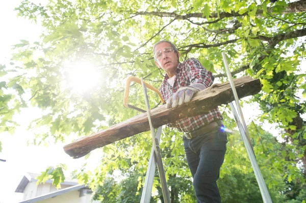 Senior man sawing a log handsaw closeup — Stock Photo, Image