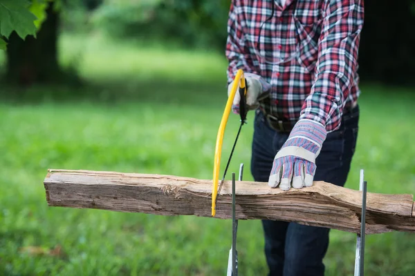 Äldre man sågar en stock handsåg närbild — Stockfoto