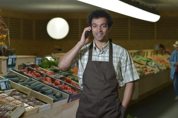 Vendedor de comestibles telefoneando en pasillo de productos de la tienda de supermercados —  Fotos de Stock