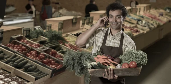 Grocery clerk phoning in produce aisle of supermarket store — Stock Photo, Image