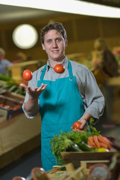 Empleado de comestibles haciendo malabares con tomates en la tienda de supermercados —  Fotos de Stock