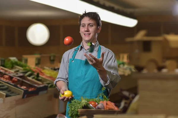 Empleado de comestibles haciendo malabares con tomates en la tienda de supermercados — Foto de Stock