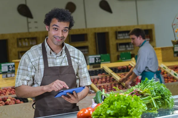 Grocery store employee reading inventory list on digital tablet — Stock Photo, Image