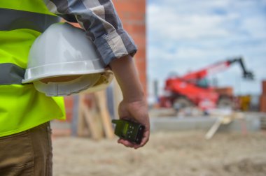 Bir kask inşaat sitenin arka planı ile holding işçi.