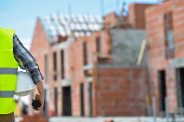 Bir kask inşaat sitenin arka planı ile holding işçi.