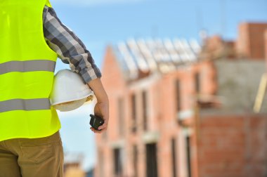 Bir kask inşaat sitenin arka planı ile holding işçi.
