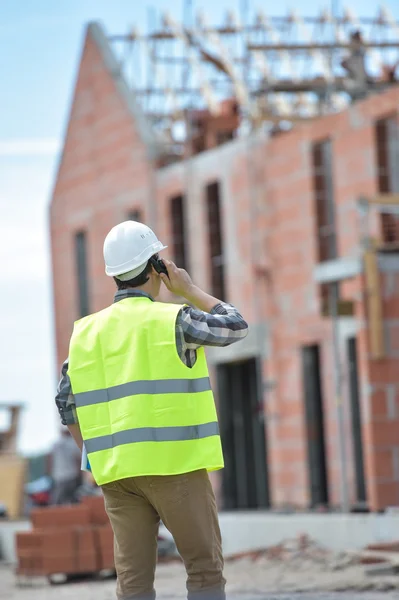 Foreman walking using walkie-talkie on construction site — Stock Photo, Image