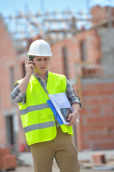 Foreman walking using walkie-talkie on construction site