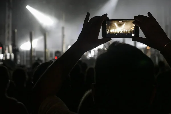 Silhouet van handen opnemen van video's op muziek concert — Stockfoto