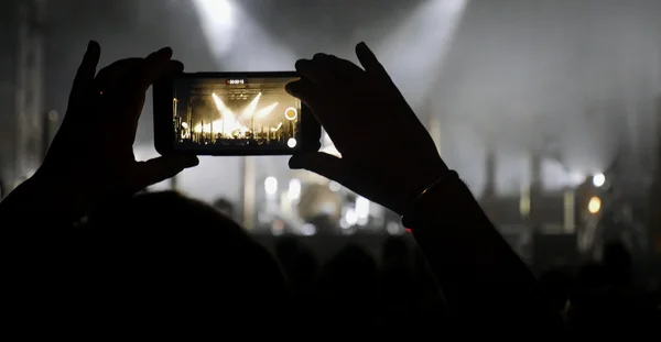 Silhouet van handen opnemen van video's op muziek concert — Stockfoto