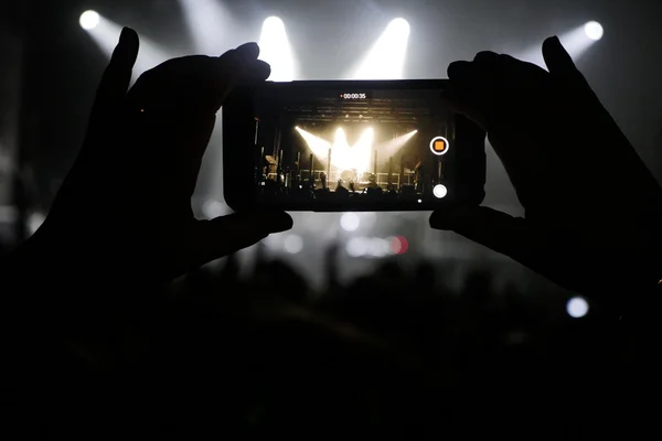 Silhueta de mãos gravação de vídeos no concerto de música — Fotografia de Stock