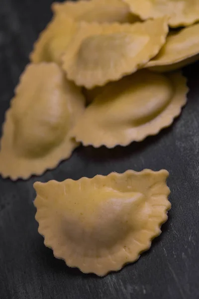 Ravioli cru saboroso com farinha e espinafre no fundo escuro, processo de fazer ravioli italiano — Fotografia de Stock