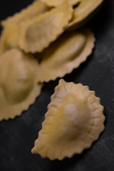 Sabrosos ravioles crudos con harina y espinacas sobre fondo oscuro, proceso de elaboración de ravioles italianos —  Fotos de Stock