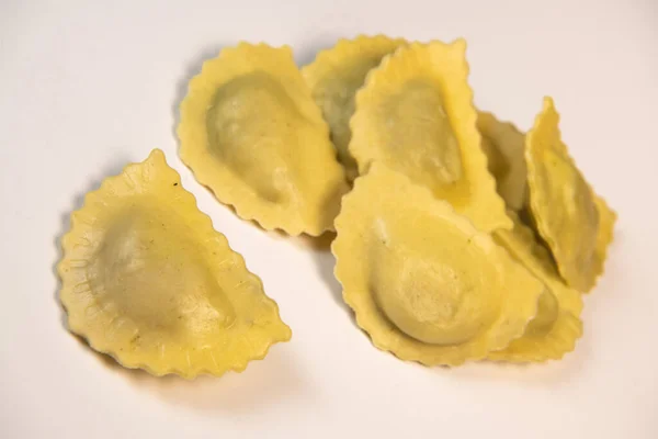 Ravioli cru saboroso com farinha e espinafre sobre fundo branco, processo de fazer ravioli italiano — Fotografia de Stock