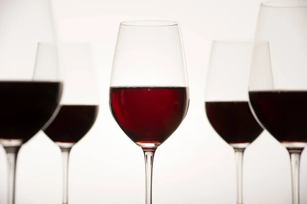 Verres avec vin de raisin rouge et bouteille sur une surface blanche brillante — Photo