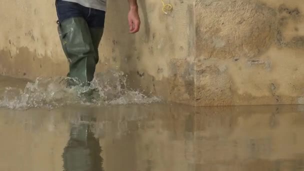 Frankrijk, La Reole, 4 februari 2021, De rivier de Garonne overstroomt haar oevers na zware regenval, Een man uitgerust met steltlopers bereikt zijn overstroomde huis — Stockvideo