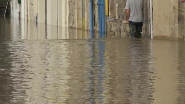 Frankrijk, La Reole, 4 februari 2021, De rivier de Garonne overstroomt haar oevers na zware regenval, Een man uitgerust met steltlopers bereikt zijn overstroomde huis — Stockvideo