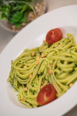 Tahta masada peynirli ve domatesli ıspanaklı spagetti.