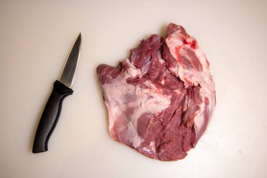 Boning a shoulder of lamb leg meat on a wooden tray, white background, Top view clipart
