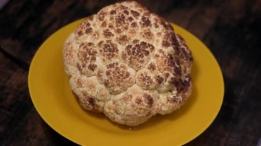 Sarı bir tabakta kavrulmuş karnabahar dönüyor.