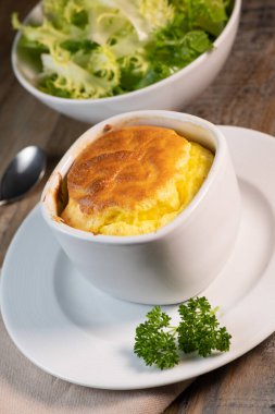 Tahta bir arka planda, kırsal kumaş üzerinde peynirli yumurta suflesi.