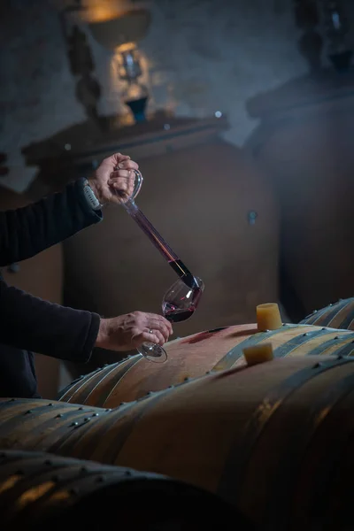 FRANKREICH, GIRONDE, SAINT-EMILION, SAMPLING EIN WEINGLAS IN EINEM BARREL MIT EINEM PIPETTE FÜR VERKOSTUNG UND VINIFIZIERUNG — Stockfoto