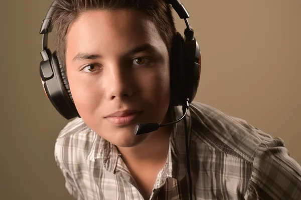 Portrait of Smiling Teenage Boy Listening to Musicon a brown bac — Stock Photo, Image