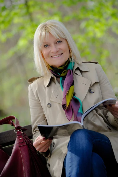 Porträt einer lächelnden Seniorin, die ein Buch liest, das auf einem — Stockfoto