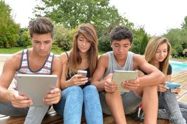 Young teenagers playing on tablet and phone clipart