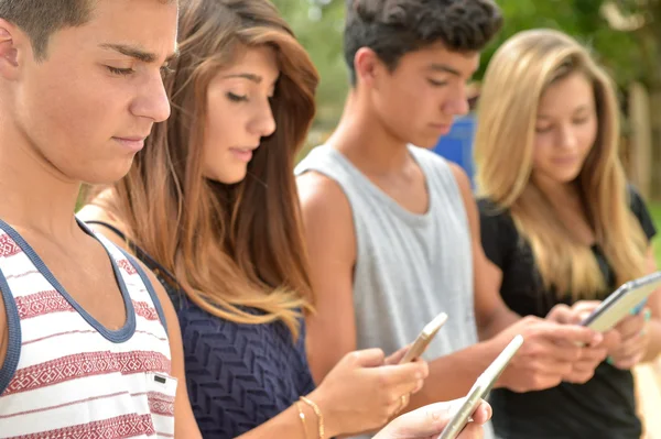 Young teenagers playing on tablet and phone — Stock Photo, Image