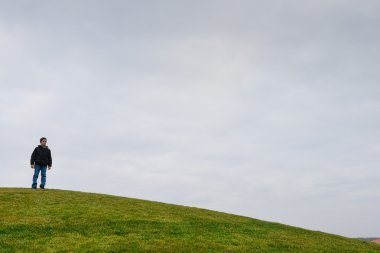 Dune ufukta yeşil çim üzerinde genç çocuk