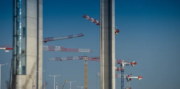 Guindastes de construção e local contra um céu azul — Fotografia de Stock