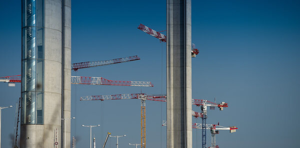 Construction cranes and site against a blue sky