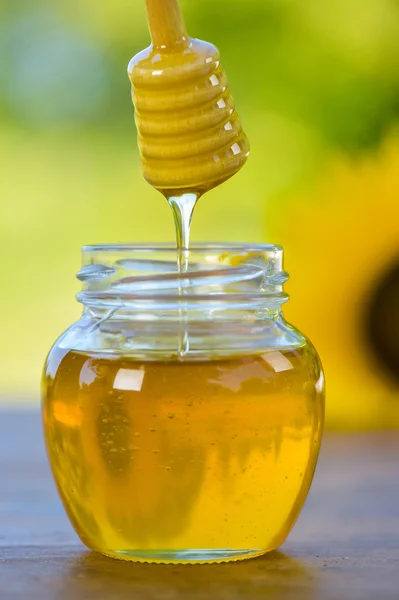 Honning drypper fra en honningske i en glasskål - Stock-foto