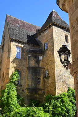 Ziyaretçiler, Sarlat, Dordogne 'daki çarpıcı ortaçağ mimarisine hayret ediyor. Karakteristik taş binaları ve açık mavi gökyüzü altındaki karmaşık ayrıntılarıyla..
