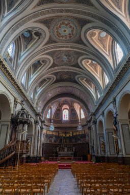 The interior of Sainte-Marie-Madeleine church features stunning architecture with intricate details, high ceilings, and decorative stained glass. The space is inviting and majestic.