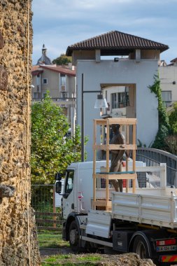 Mairie Mont de Marsan yakınlarında park etmiş bir kamyon bir heykel teslim ediyor. Sahne, arka planda açık bir gökyüzü ve yerel mimari ve sanatın sergilendiği yeşil ağaçları yakalıyor..