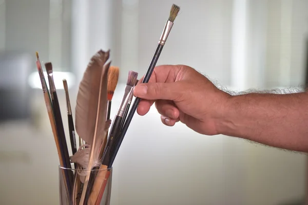 Mano de pintor tomando un pincel en una olla — Foto de Stock