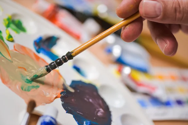 Mano del artista aplicando gouache de pintura en la hoja de dibujo — Foto de Stock
