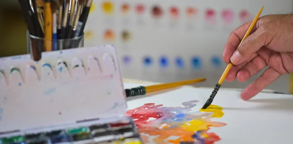 Konstnärens hand tillämpa färg gouache på ritningen blad — Stockfoto