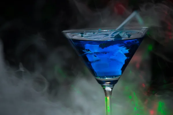 Fire blowing out of blue lagoon glass/close-up with black backgr — Stock Photo, Image