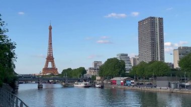 Eyfel halkı Paris 'teki nehir kıyısında yürüyor. Eyfel Kulesi arka planda dik duruyor. Yüksek kalite 4k görüntü